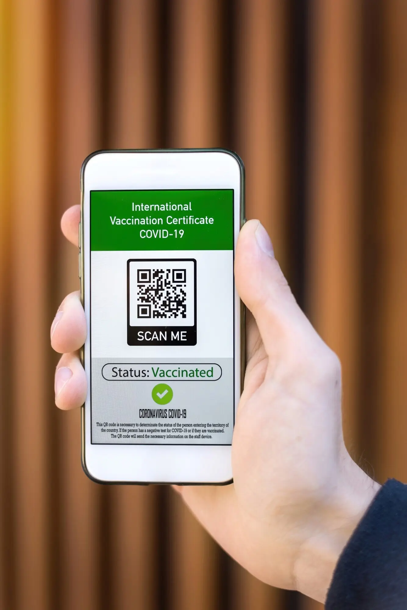 Мужская рука держит смартфон с QR-кодом международного сертификата вакцинации от COVID-19.